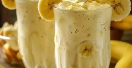 Batido cremoso de piña y banana servido en vaso con hielo, decorado con rodajas de fruta
