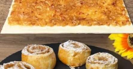 Roulés feuilletés aux pommes dorés et croustillants sur une assiette en céramique, garnis de sucre glace et servis avec une cuillère de crème fraîche.
