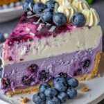 Cheesecake de arándanos con base de galleta, crema batida y frutos frescos como decoración