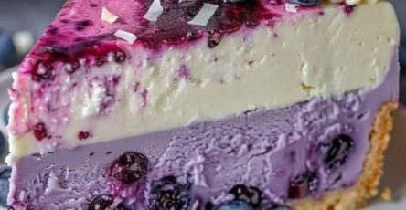 Cheesecake de arándanos con base de galleta, crema batida y frutos frescos como decoración