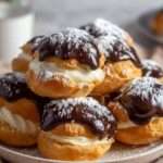 profiteroles au chocolat maison nappées de ganache brillante sur une assiette blanche