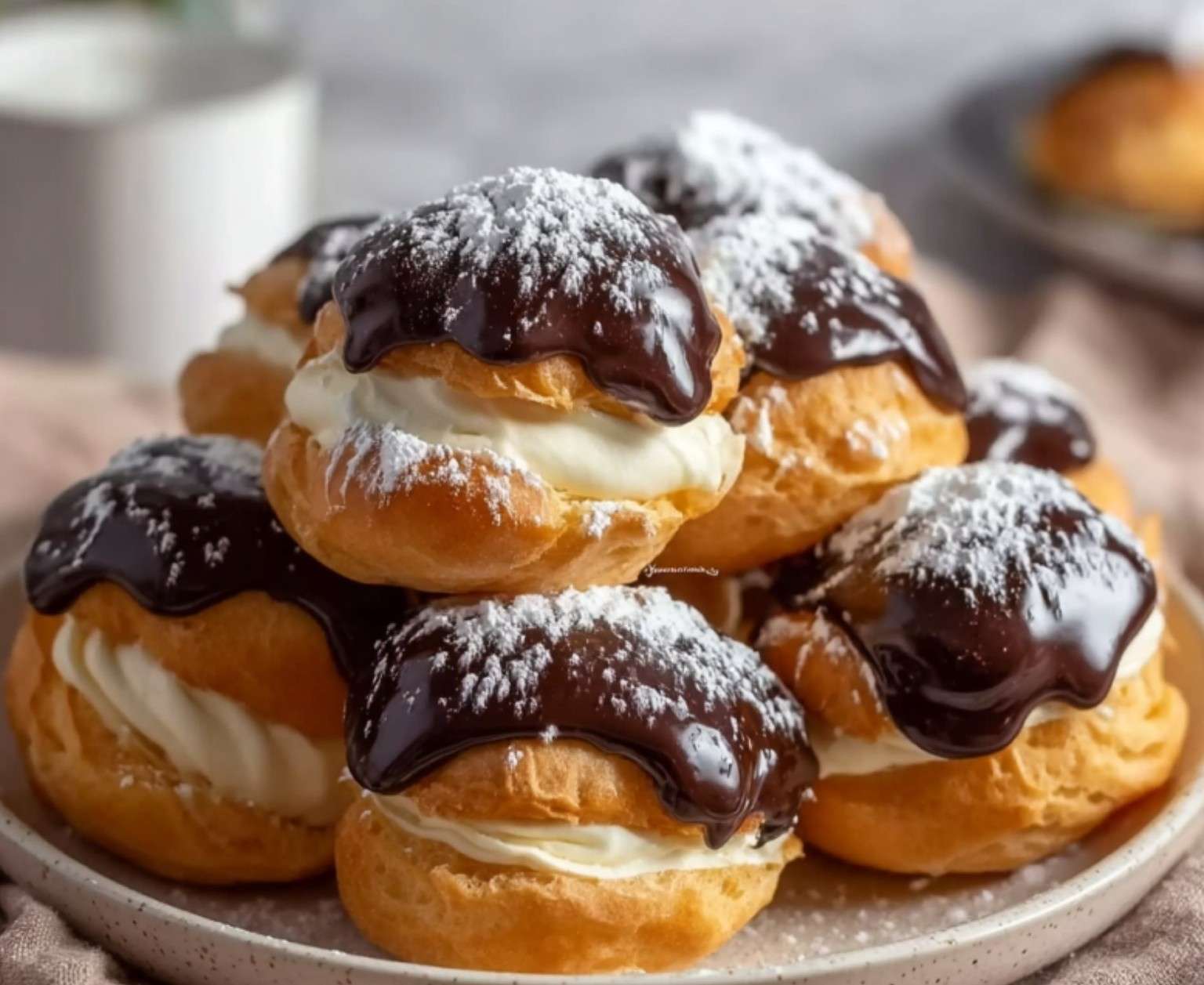 profiteroles au chocolat maison nappées de ganache brillante sur une assiette blanche