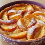 Clafoutis aux nectarines doré dans un plat rond avec quartiers de fruits visibles