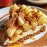 Gros plan sur une part de cheesecake pomme et crumble croustillant, nappée de caramel et de cacao, servie sur une assiette.