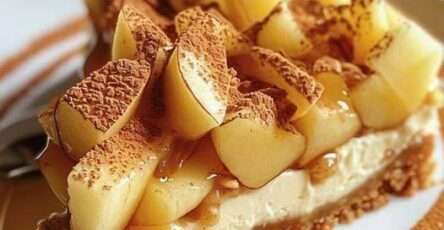 Gros plan sur une part de cheesecake pomme et crumble croustillant, nappée de caramel et de cacao, servie sur une assiette.