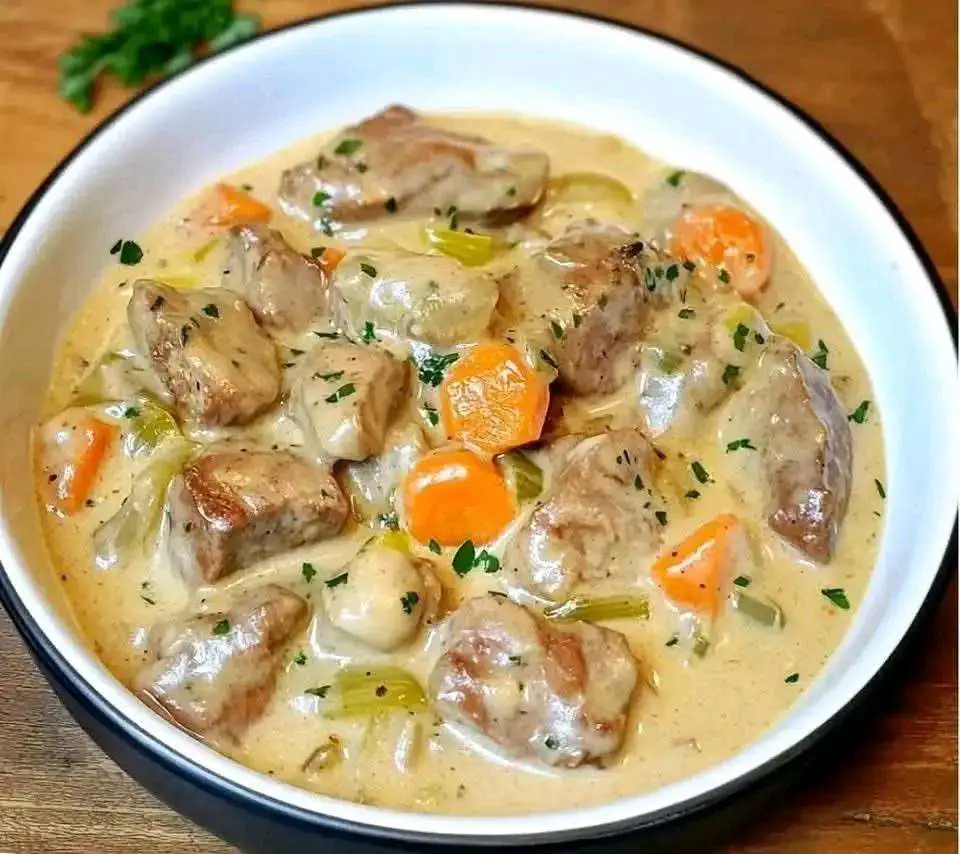 Blanquette de veau à l’ancienne servie dans une cocotte, viande fondante, légumes colorés et sauce blanche onctueuse, parsemée de persil frais.