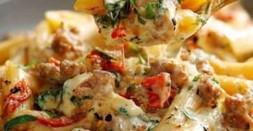 Assiette de pâtes penne nappées de sauce crémeuse à la viande hachée, gratinées au fromage fondant, décorées de basilic frais.