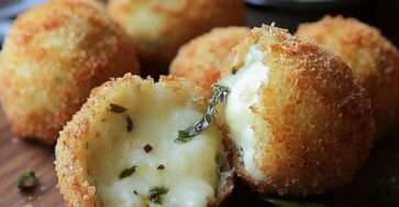 Croquettes de mozzarella dorées et croustillantes, coupées en deux, montrant leur cœur fondant, servies avec sauce tomate et feuilles de basilic frais.