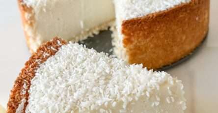 Flan coco épais, fondant, sur base dorée de noix de coco, servi frais et saupoudré de coco râpée sur assiette claire.