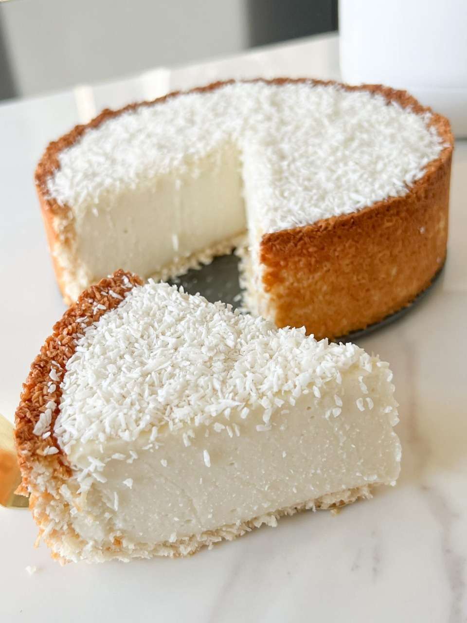 Flan coco épais, fondant, sur base dorée de noix de coco, servi frais et saupoudré de coco râpée sur assiette claire.