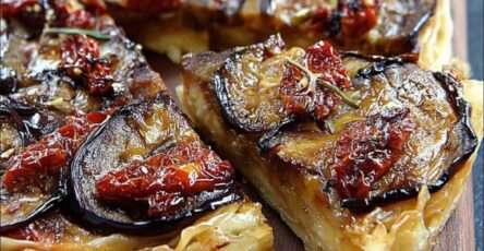 Tatin d’aubergines aux tomates séchées, dorée et fondante, servie sur une assiette blanche avec salade verte et herbes fraîches.