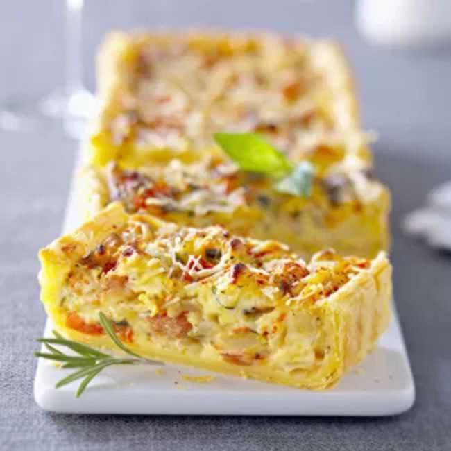 Flan provençal – Tarte salée dorée, légumes méditerranéens, courgettes, tomates cerises, crème, gruyère, part gourmande sur fond rustique.
