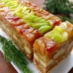 Tranches de terrine brillante aux pommes et poires caramélisées, décorées de lamelles de pomme verte, servies sur une assiette raffinée.