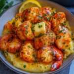 Assiette élégante de bouchées de homard au beurre à l’ail posées sur une purée de pommes de terre au safran.