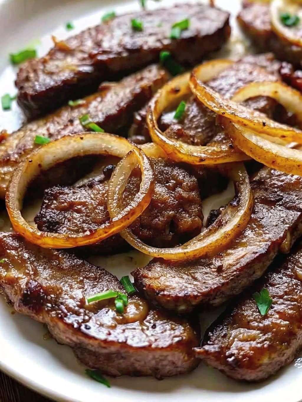 Assiette de foie de bœuf poêlé nappé d’oignons caramélisés et persil frais.