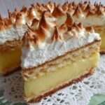 Gâteau citron-meringue en couches avec génoise moelleuse, crème au citron et meringue dorée au chalumeau.