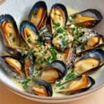 Moules au beurre persillé et ail servies dans une cocotte avec persil frais
