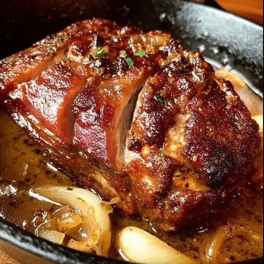Rouelle de porc confite au four nappée d’une sauce aux oignons et à l’ail
