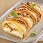 Feuilleté tressé au camembert fondant avec pommes et noix sur une assiette dorée