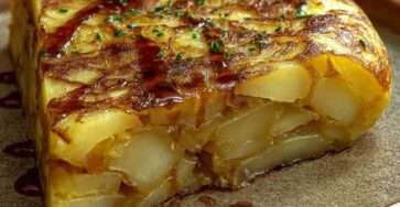 Tranche de tortilla espagnole dorée aux pommes de terre et oignons, servie sur une assiette rustique.