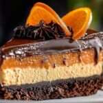 Cheesecake au chocolat et à l’orange avec ganache brillante, décoré de tranches d’orange confite et de copeaux de chocolat sur une assiette élégante.