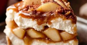 Cheesecake aux pommes caramélisées avec un nappage doré au caramel et des morceaux de pommes fondantes sur une base biscuitée croustillante.