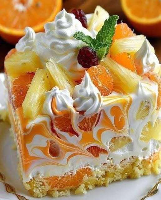 Cheesecake sans cuisson à l’orange et à l’ananas, garni de crème fouettée, tranches d’orange et morceaux d’ananas, sur base de biscuits Graham dorés.