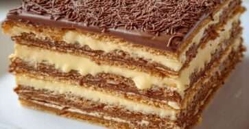 Part de gâteau Petit Beurre au café sans cuisson, alternant couches de biscuits imbibés et de crème vanillée, décorée de vermicelles de chocolat.