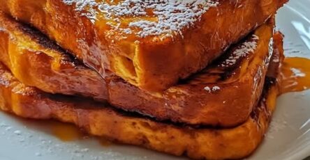 Tranches de pain perdu dorées nappées de sirop d’érable, servies avec crème fouettée et épices de citrouille sur une assiette d’automne.