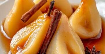 poires pochées au miel et à la cannelle servies chaudes avec leur sirop doré, décorées d’un bâton de cannelle et d’une étoile de badiane.