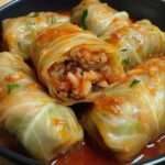 Rouleaux de chou farcis au bœuf et au riz nappés de sauce tomate, servis chauds avec persil frais haché.