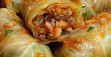 Rouleaux de chou farcis au bœuf et au riz nappés de sauce tomate, servis chauds avec persil frais haché.