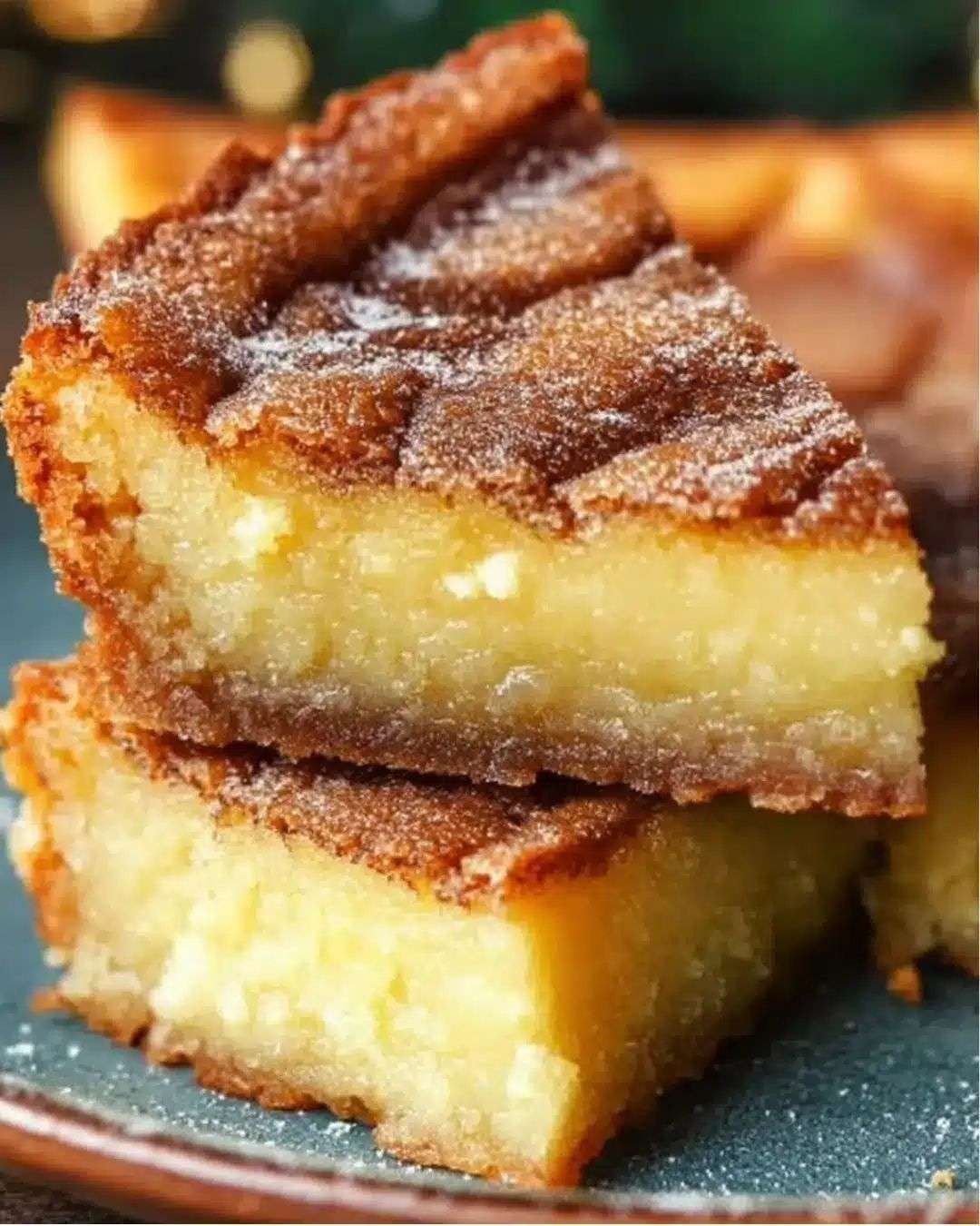 Gâteau moelleux frangipane au rhum doré, saupoudré de sucre glace et garni d’amandes effilées sur une assiette de dessert.