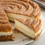 Cheesecake façon churros doré au sucre et à la cannelle, avec une garniture fondante au fromage à la crème dans un moule rectangulaire.