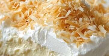 Photo d’un dessert Coconut Cream Lush en couches crémeuses avec croûte de biscuits Graham, crème fouettée et copeaux de noix de coco grillés.