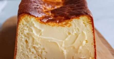 Cheesecake basque brûlé en cake, doré et caramélisé sur le dessus, tranché pour révéler sa texture fondante et crémeuse.