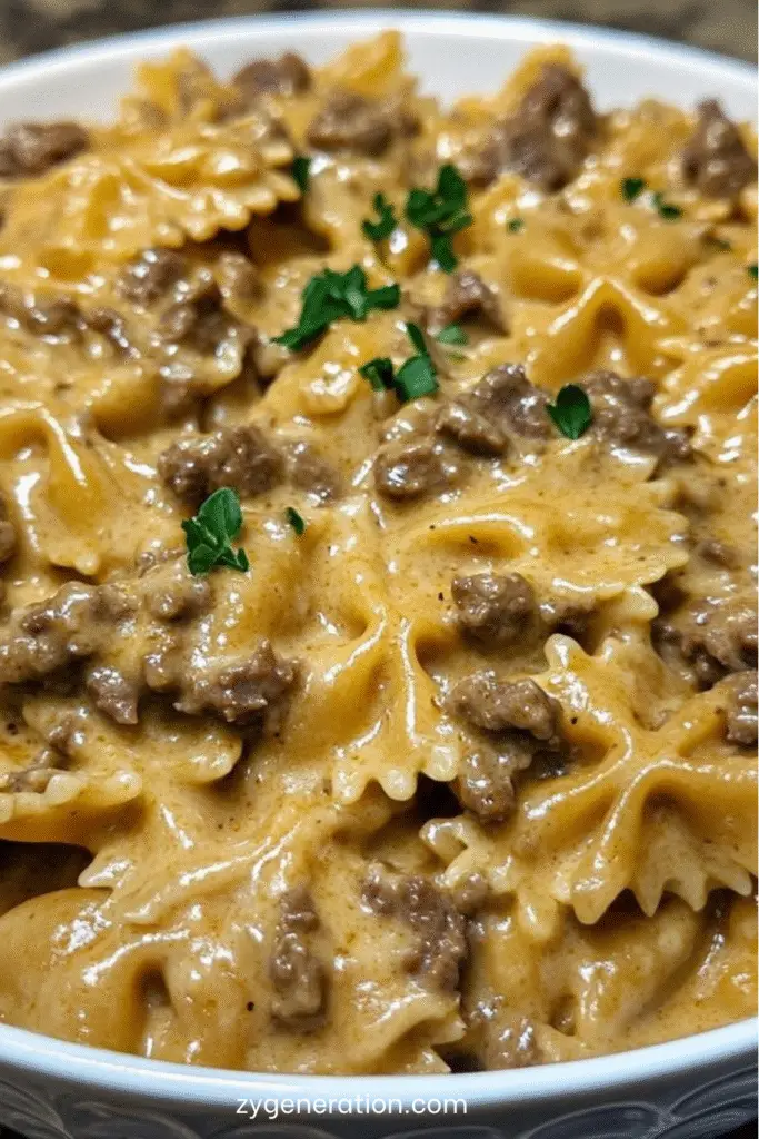 Assiette de pâtes papillon à la viande hachée et sauce crémeuse au parmesan, décorée de persil frais et servie chaude dans une poêle rustique.