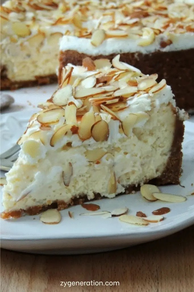 Cheesecake à l’amande et à l’Amaretto, surmonté d’amandes grillées dorées, sur fond de table en bois clair, tranché pour révéler sa texture onctueuse et dorée.