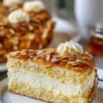 Gâteau allemand Bienenstich coupé en parts, avec crème vanillée au mascarpone, pâte briochée moelleuse et croûte dorée d’amandes au miel.