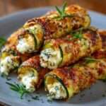 Rouleaux de courgettes croustillants au fromage dorés au four, servis avec sauce au yaourt et persil frais.