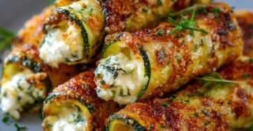 Rouleaux de courgettes croustillants au fromage dorés au four, servis avec sauce au yaourt et persil frais.