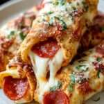 Rouleaux de pizza au pepperoni dorés au four, garnis de fromage fondant et de sauce tomate, servis sur une planche en bois.