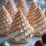 Meringues en forme de sapins de Noël décorées avec perles sucrées et étoiles sur une plaque de cuisson.