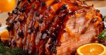 jambon rôti laqué à l’orange et au miel, décoré de rondelles d’orange et herbes fraîches