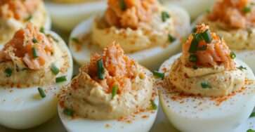 Photographie d’œufs mimosa garnis au saumon ou au thon, décorés de paprika et d’herbes fraîches, disposés sur une assiette élégante.