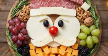 Plateau apéritif représentant un Père Noël réalisé avec saucisson, fromages, olives, tomate cerise, fruits et romarin, présenté en forme de visage festif.