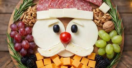 Plateau apéritif représentant un Père Noël réalisé avec saucisson, fromages, olives, tomate cerise, fruits et romarin, présenté en forme de visage festif.