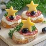 Photographie de toasts festifs garnis de fromage frais, de saucisson, d’étoiles de fromage, d’olives noires et de persil, joliment présentés sur un plateau.