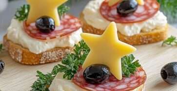 Photographie de toasts festifs garnis de fromage frais, de saucisson, d’étoiles de fromage, d’olives noires et de persil, joliment présentés sur un plateau.