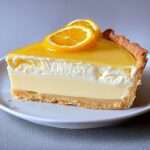 Tarte crémeuse aux agrumes avec glaçage citron orange brillant et décoration de tranches d’agrumes.